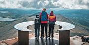 lady and 2 children stand on top of Mount Gausta